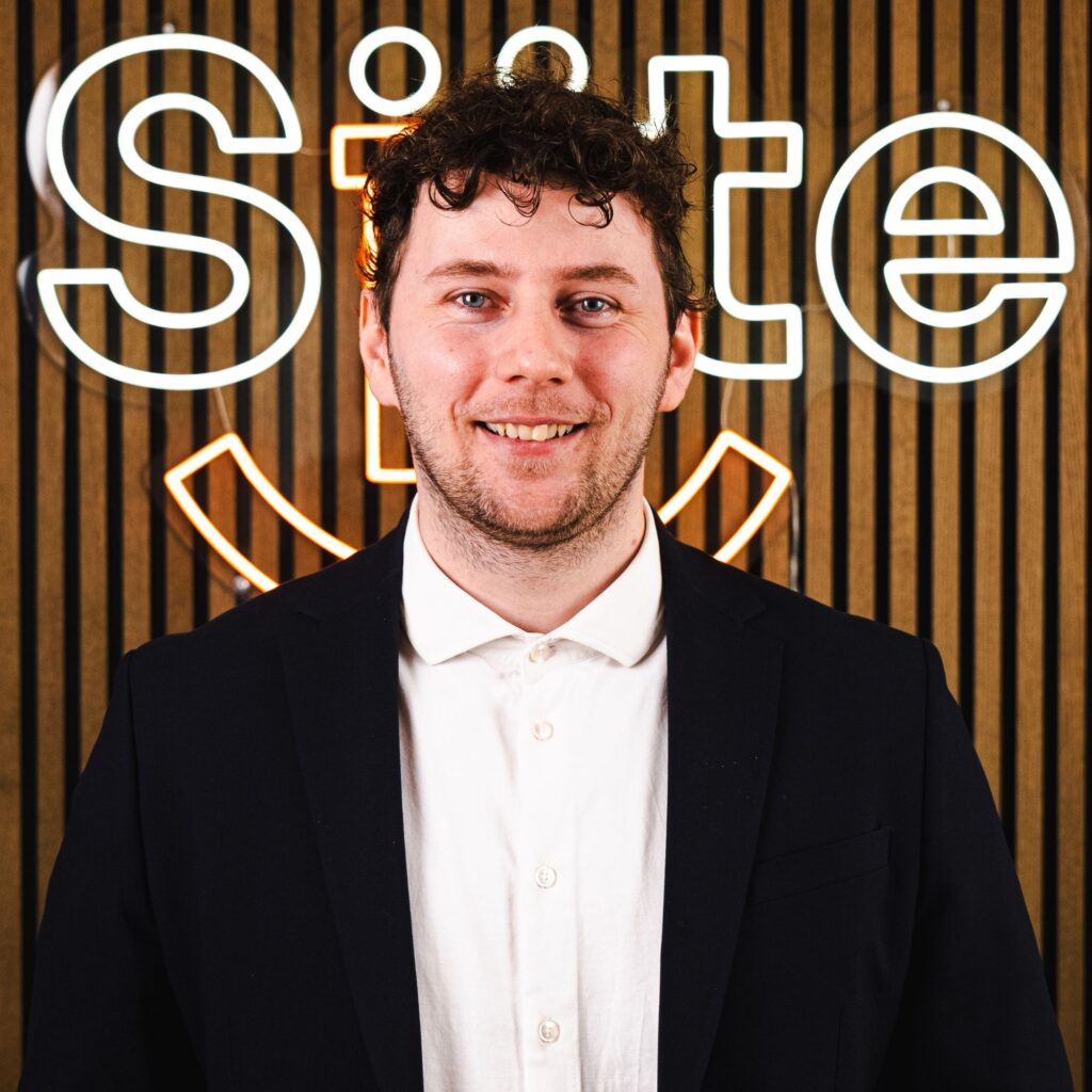 Mand foran neonlys skilt med jakkesæt