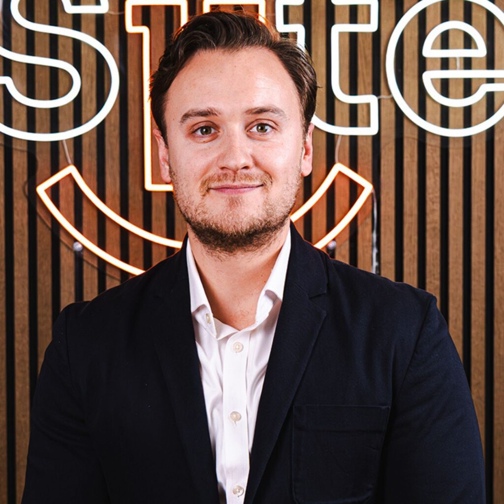 Mand foran neonlys med smilende ansigt.