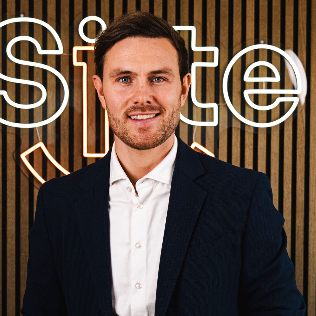 Mand i jakkesæt foran et skilt