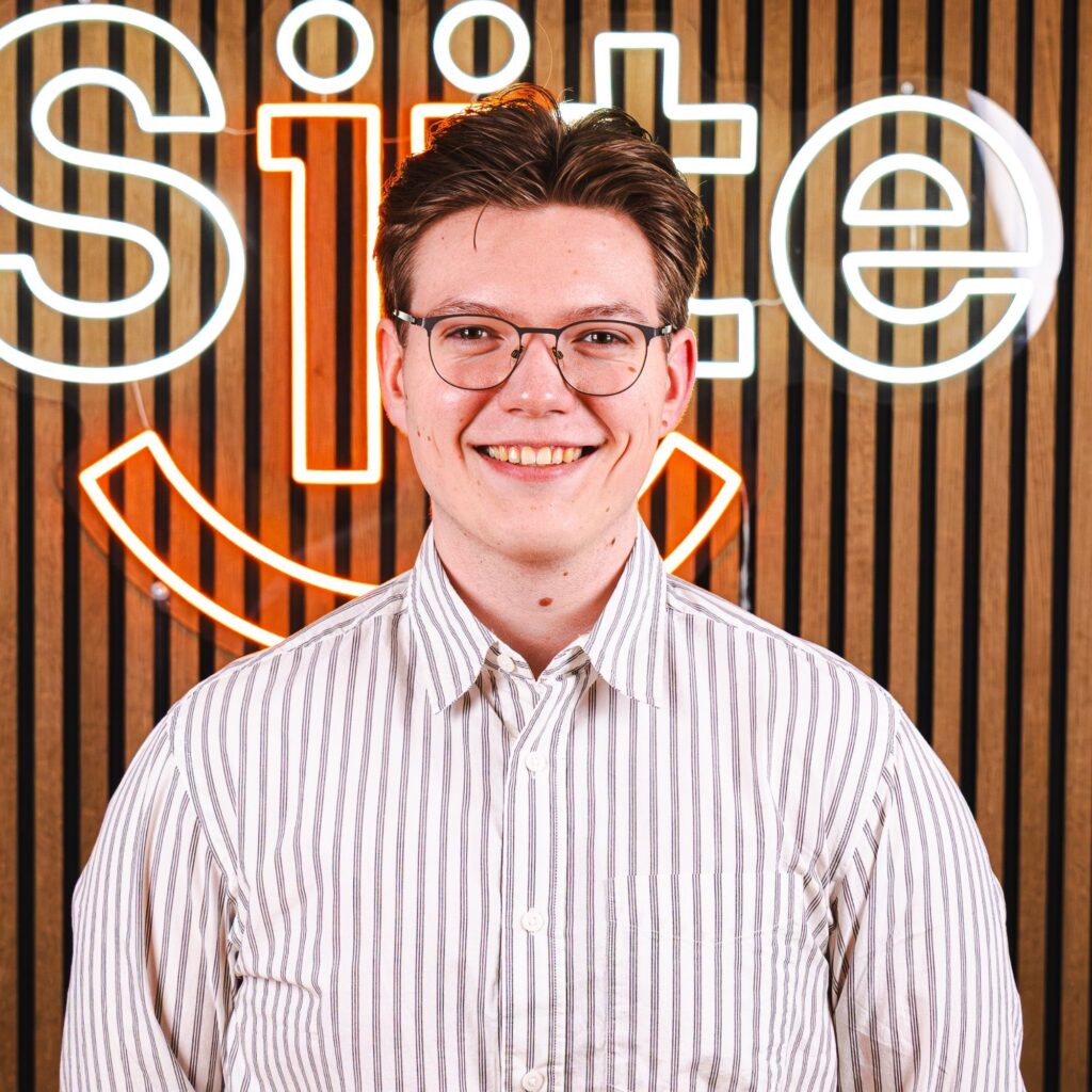 Mand smiler foran neonskilt