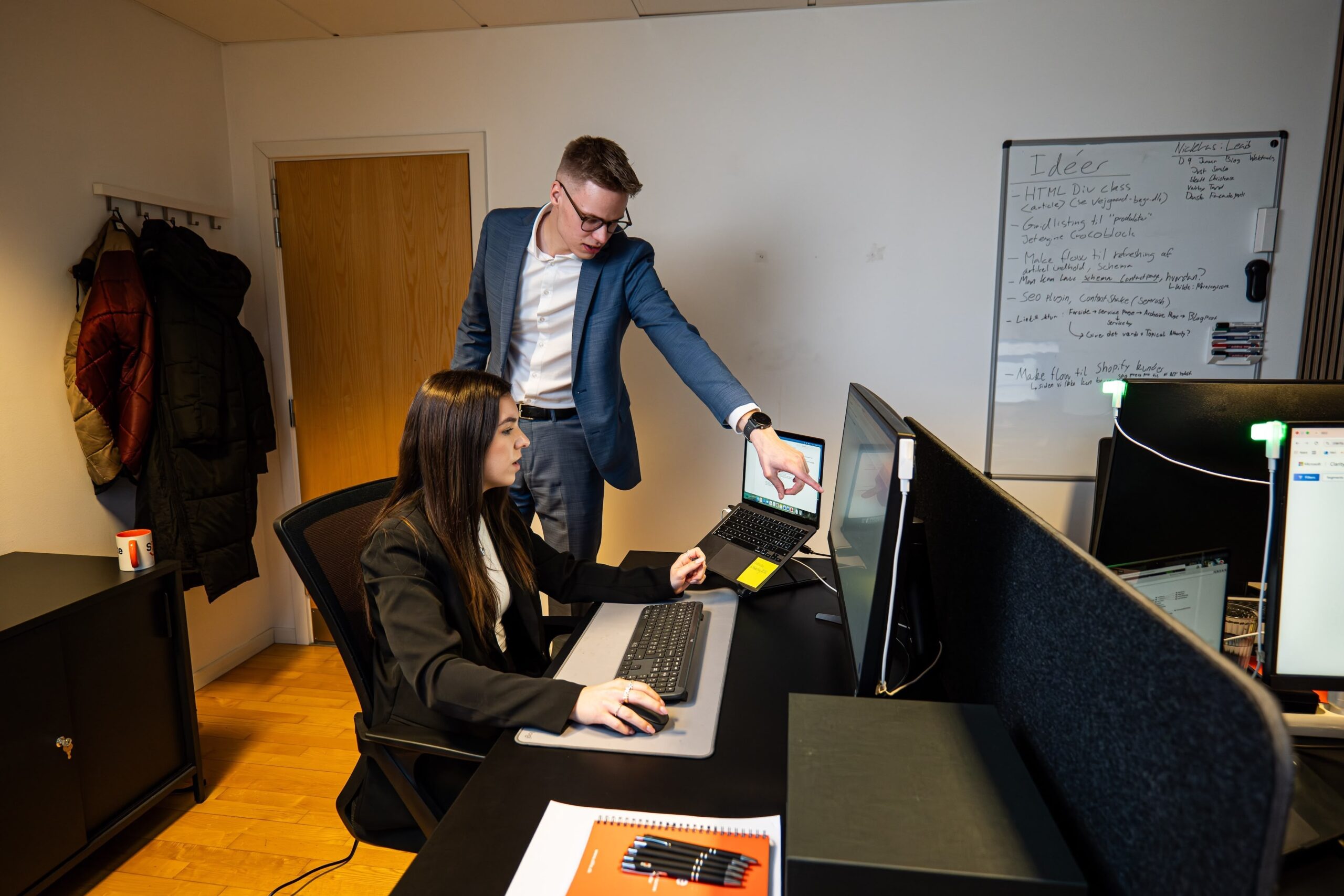 To kontormedarbejdere samarbejder foran computer