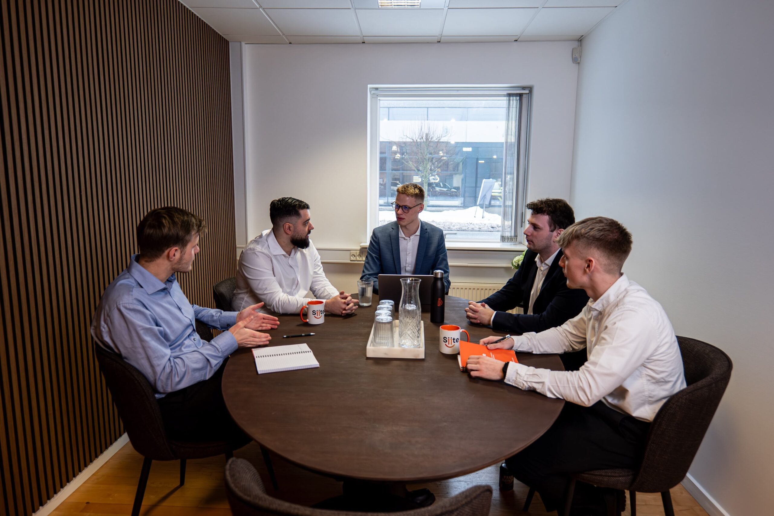 Møde i en moderne kontorbygning med fem personer