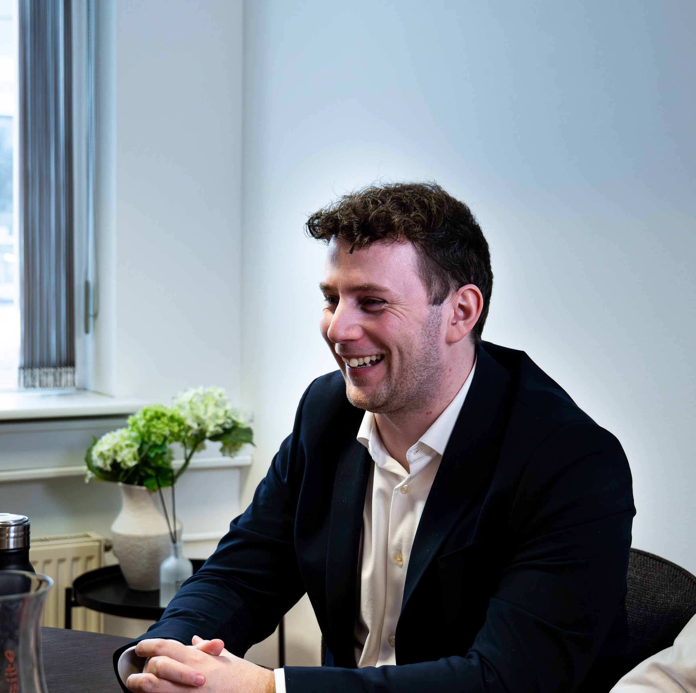 Smilende mand i jakkesæt ved kontorbord