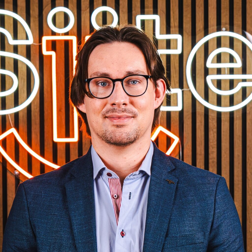 Mand foran lysende skilt med briller og jakkesæt.